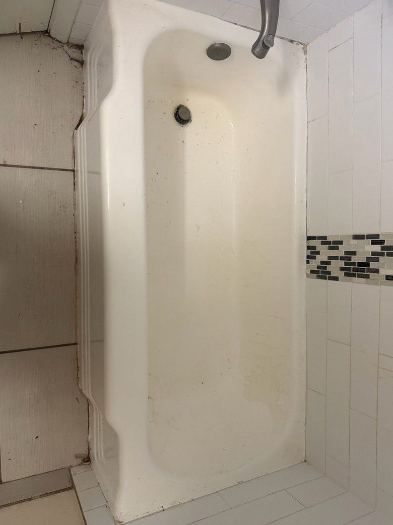 Before: worn, discolored bathtub with a tiled surround.