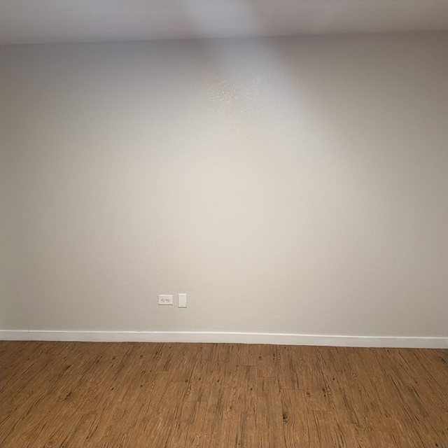 After: the same living-room wall after painting, with an even finish.