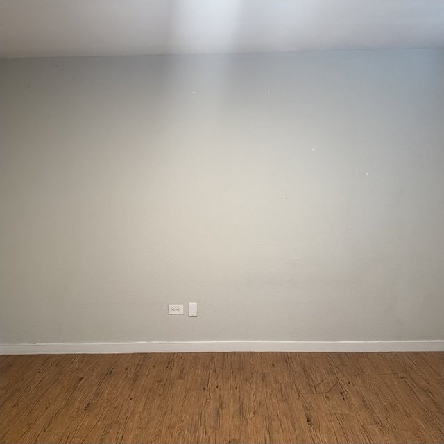 Before: apartment living-room wall with patches and marks.